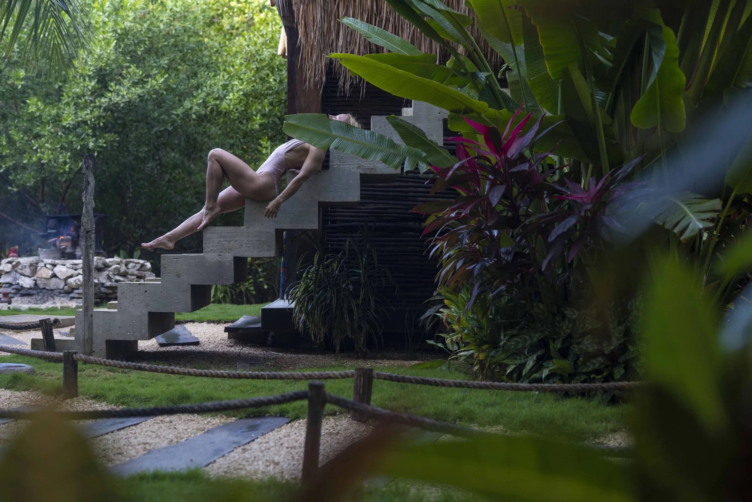 Michelle stretched across a stone staircase in a tropical garden, Tulum