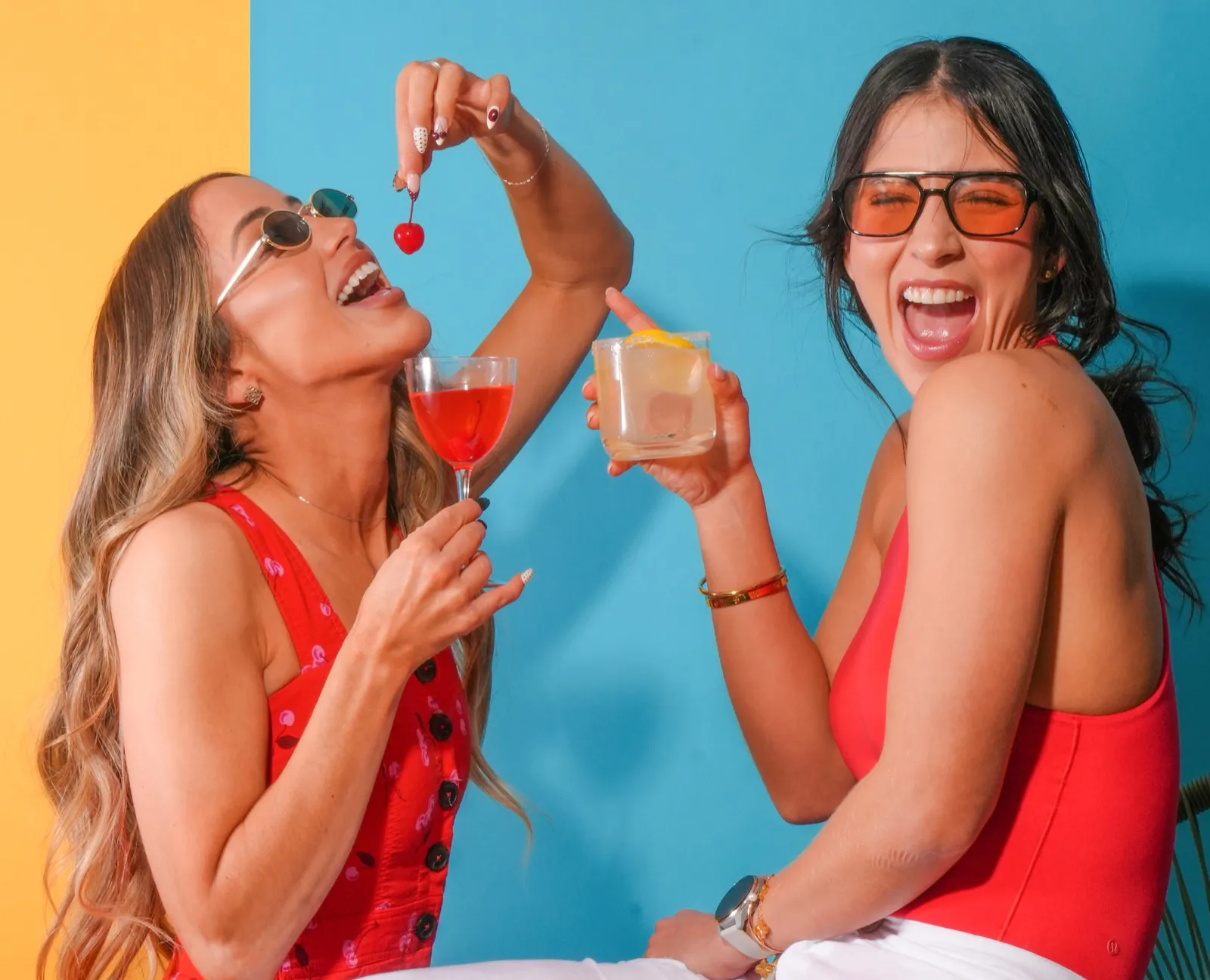 Two models laughing and toasting with cocktails