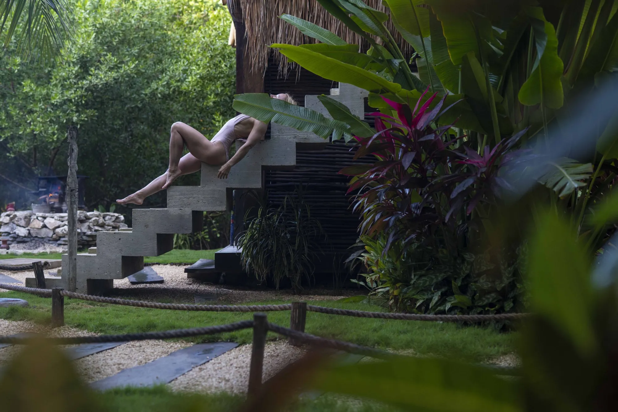 Yoga pose on dark wooden steps surrounded by tropical plants at Yäan Wellness Spa